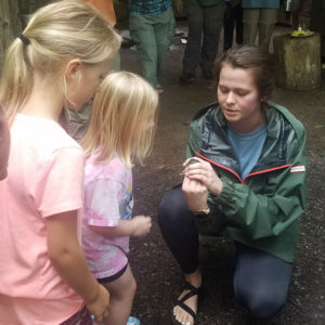 Anna Cameron shows two children a bird during bird banding at Tremont Institute