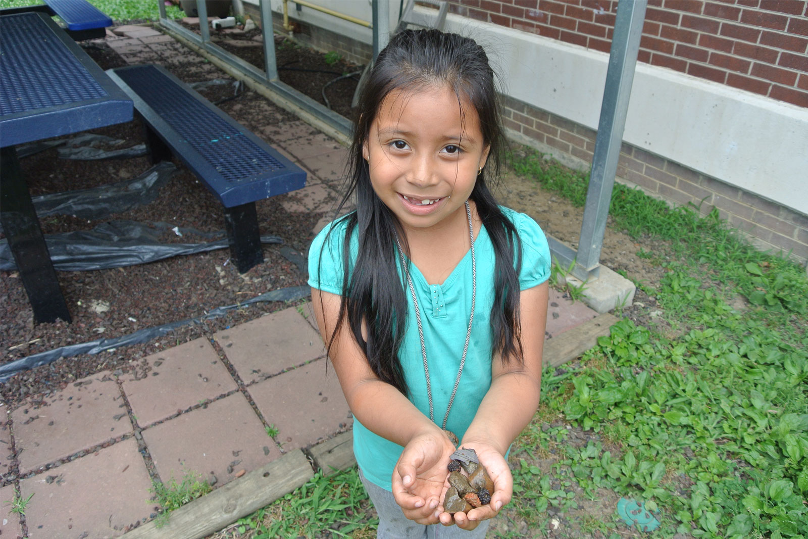 A young student holds rocks in her hands