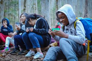 School children laugh around a campfire
