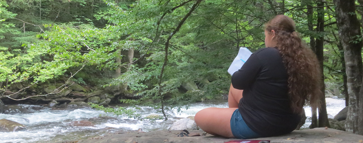 A high school student sits by the river at Maryville Colleges's Great Smokies Experience at Tremont in the Great Smoky Mountains National Park.